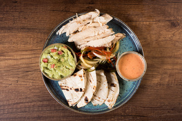 Chicken fajitas with grilled onions and bell peppers and serve with flour tortillas on rural wooden board