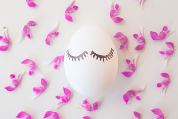 Easter eggs on a white background in pink spring flowers with copyspace. Minimalism concept, Top view. Mock up. Flat lay