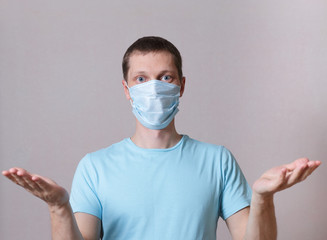 A young man in a medical mask in self-isolation, makes a questioning gesture with his hands when it's all over. concept