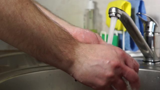 Hands carefully soap each other with soap under the tap with water for hygiene