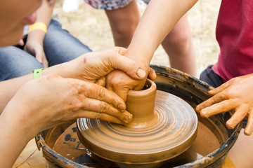 A close up view on ceramic production process on potter's wheel with children. Clay crafts with kids concept.