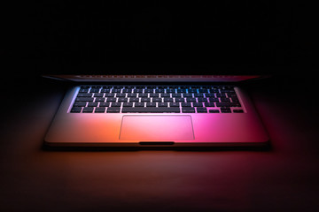a laptop in the dark with colourful reflection