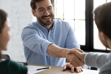 Happy businessmen shake hands greeting getting acquainted at office meeting, smiling male business partners handshake close deal make agreement after successful negotiation in boardroom