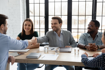 Smiling businessman shake hands greeting getting acquainted at office meeting, happy male business partners handshake close deal make agreement after successful negotiation at boardroom briefing