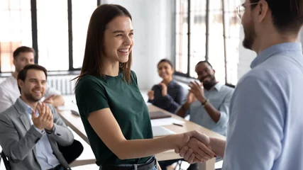 Poster Businessman shake hand of excited Caucasian female employee greeting with achievement or success at office meeting, male boss or CEO handshake happy woman worker congratulate with work promotion © fizkes