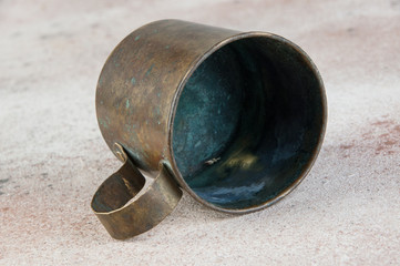 Old brass mug with handle on concrete background