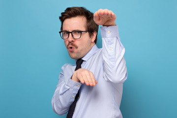 Funny angry handsome young man in blue shirt standing in karate gesture and ready to attack. © RealPeopleStudio