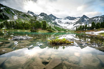 Green lake between mountains in cloudy day