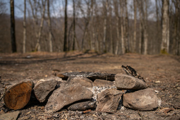 Fireplace from wood and stones with ashes and  without a fire in a romantic forest early in early spring