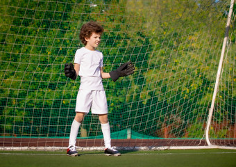 Summer soccer tournament for young kids. football club. emotions and joy of the game. Young goalie. Kids - soccer champion. Boy goalkeeper in football sportswear on stadium with ball. Sport concept.