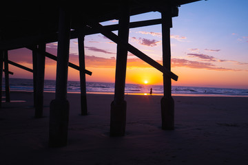 View of sunset over beach with pier in foreground