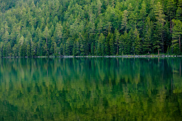 Fototapeta na wymiar Green lake between mountains in cloudy day