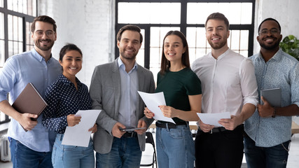Group portrait of smiling diverse young multiethnic businesspeople posing together in modern office, happy motivated multiracial employees show unity and success, teamwork, cooperation concept