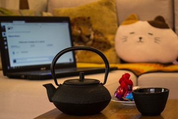 cast iron kettle and cup in front of sofa and notebook
