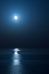 Fantastic blue sea background. Mediterranean Sea at night. Moon reflecting in a sea. Vertical image.