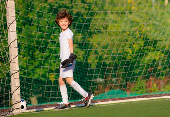 Summer soccer tournament for young kids. football club. emotions and joy of the game. Young goalie. Kids - soccer champion. Boy goalkeeper in football sportswear on stadium with ball. Sport concept.