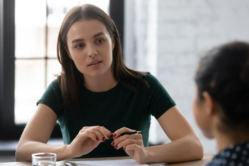 Concentrated female Caucasian employee talk with colleague discuss business ideas at office briefing together, focused woman worker speak brainstorm negotiate with coworker at boardroom meeting