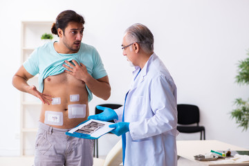 Fototapeta premium Injured young man visiting experienced male doctor