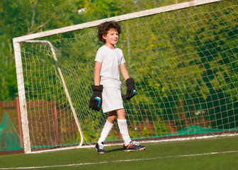 Summer soccer tournament for young kids. football club. emotions and joy of the game. Young goalie. Kids - soccer champion. Boy goalkeeper in football sportswear on stadium with ball. Sport concept.