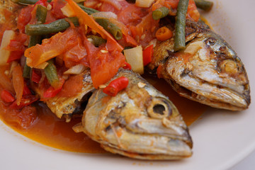 fried fish with chili sauce and tomatoes on top close up shot
