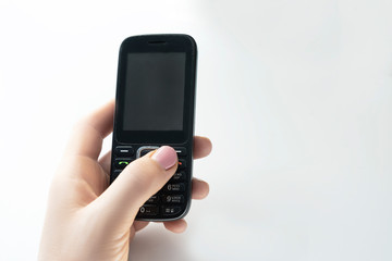 Push-button telephone in a female hand on a white background

