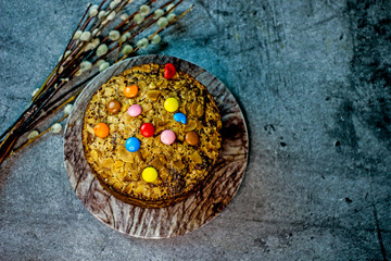 Obraz na płótnie Canvas Tasty easter cake with almond flakes on a dark background, next to a pussy-willow twig. The concept of Easter baking for the holiday, copy space