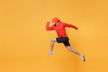 Fototapeta na wymiar Side view of strong young fitness sporty guy 20s sportsman in hat hoodie shorts in home gym isolated on yellow background in studio. Workout sport motivation lifestyle concept. Jumping like running.