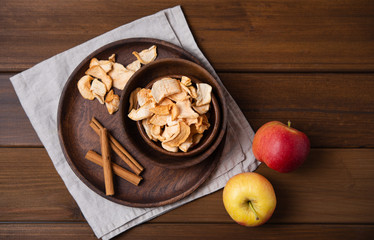 sweet homemade Apple chips baked with cinnamon in wood bowl on wooden background. Vegan and dietary product