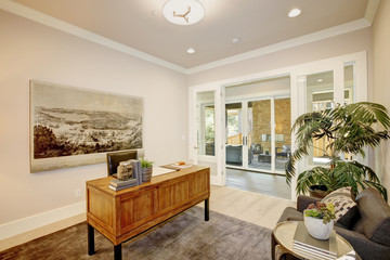 Light home office features a wooden desk. Luxury American modern home.
