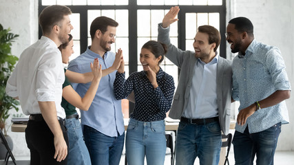 Overjoyed multiracial colleagues have fun celebrate shared business victory or win at workplace,...