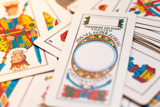Triestine cards, old european game originating from northern italy laying on the wooden table. Flat lay with ace of denars in focus, italian language on the card