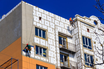 Styrofoam insulation of high-rise building. Rope access working. Concept of industrial alpinism