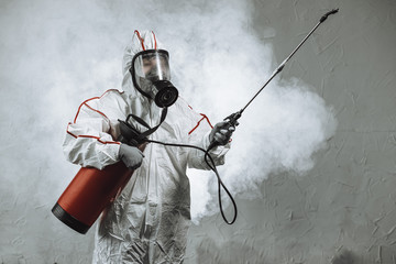 professional disinfector wearing protective biological suit and gas-mask conducts disinfection against coronavirus global pandemic warning and danger. COVID-19, coronavirus concept