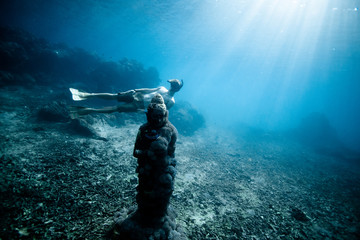 Diver looking at statue underwater