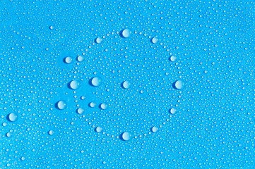 Drops of water in the form of a dial are scattered on a wet blue background. A circle of water droplets with large splashes on one side. Abstract blue background.