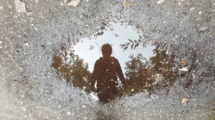 Reflection Of Woman In Puddle On Street