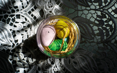 Wielkanocne pisanki w słoiku stojącym na koronkowym obrusie. © Grzegorz