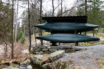 stacked canoe boats in forest near lake in Norway, frontal view