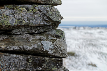 lichen covered rock cairn close up in focus with blurred mountain background in Norway, on route to Vidden, Scandinavian nature in winter