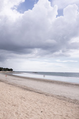 Deserted beach on the island of Bali. Clouds and clouds with rain of dark blue color. Sandy beach with sea and ocean. Tropical view. Hurricane.