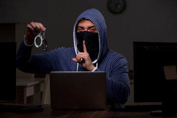 Male hacker hacking security firewall late in office