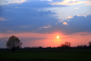 Kolorowy zachód słońca nad obszarem wiejskim, kolorowe chmury.