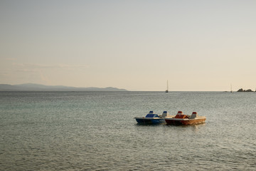 Fototapeta na wymiar Two pedal boats floating on water in bay close to Capo Testa in Sardinia,