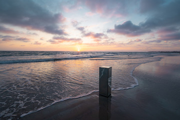View of mirrored pillar on beach during sunset