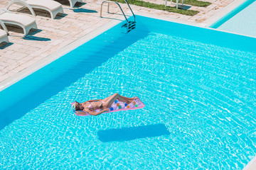 Young beautiful woman enjoying summer vacation in luxury swimming pool