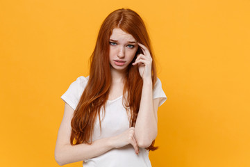 Preoccupied young redhead woman girl in white blank empty t-shirt posing isolated on yellow wall background studio portrait. People emotions lifestyle concept. Mock up copy space. Put hand on head.