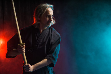real caucasian mature kendo fighter ready to fight with enemy using bamboo sword shinai . traditional japanese martial art concept, isolated over smoky space