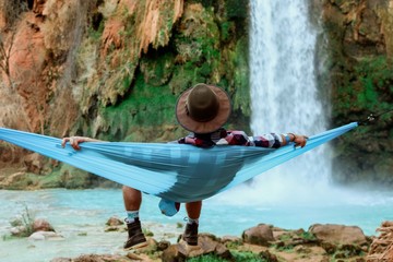 Rear view of man relaxing in hammock by waterfall