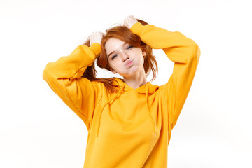 Funny young redhead woman girl in yellow hoodie posing isolated on white background studio portrait. People lifestyle concept. Mock up copy space. Having fun hold hair like ponytails, blowing cheeks.