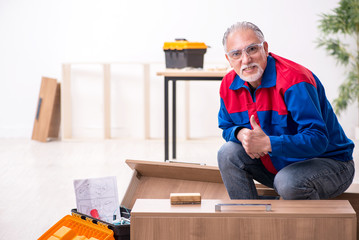 Old male carpenter working indoors